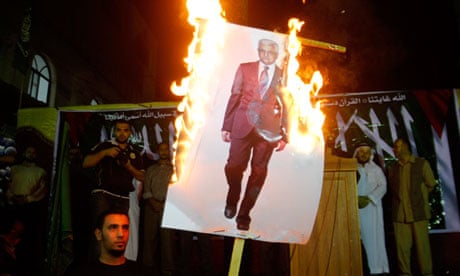 Palestinian refugees burn an image of Mahmoud Abbas