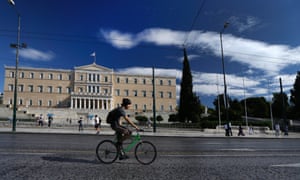 A cyclist drives in front of the Greek Parliament in central Athens, Monday, Nov. 5, 2012.