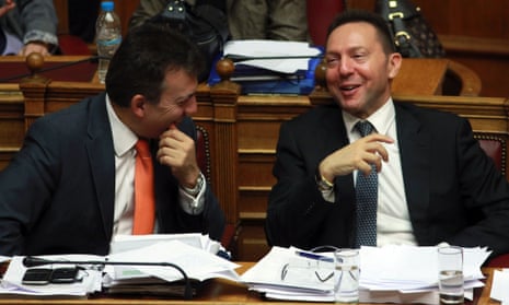 Greece's Finance Minister Yannis Stournaras, right, and Labour Minister Yiannis Vroutsis laugh as they speak with each other during a parliament meeting in Athens, Wednesday, Nov. 7, 2012. 