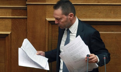 Greece's Finance Minister Yannis Stournaras holds papers after his speech at a parliament meeting in Athens, Wednesday, Nov. 7, 2012.