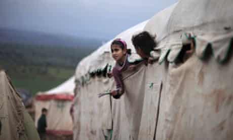 Syrian girls who fled their homes with their families peek out of their makeshift school at a camp for displaced Syrians in the village of Atmeh, Syria. This tent camp sheltering some of the hundreds of thousands of Syrians uprooted by the country's brutal civil war.