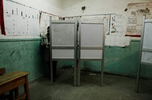 Egypt Referendum: An Egyptian woman stands behind a screen at a polling station during a vote on Egypt's draft constitution