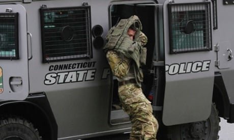 A Connecticut state police officer puts on his vest next to his armored vehicle outside St Rose of Lima Roman Catholic Church in Newtown, Connecticut.