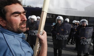 A protester holds a banner in front of a police formation during an anti-austerity rally in Athens December 19, 2012.