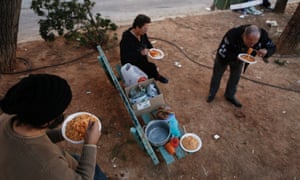 People eat pasta at a soup kitchen in a small square at Keratsini suburb, west of Athens December 13, 2012.