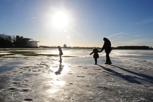 cold  uk weekend weather: People walk on frozen flood water at York Racecourse