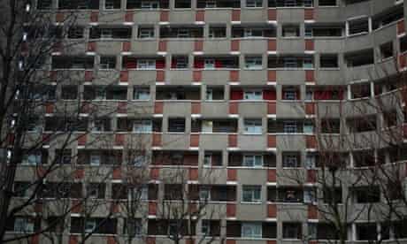 A person looks out from a balcony on a tower block in east London, UK.