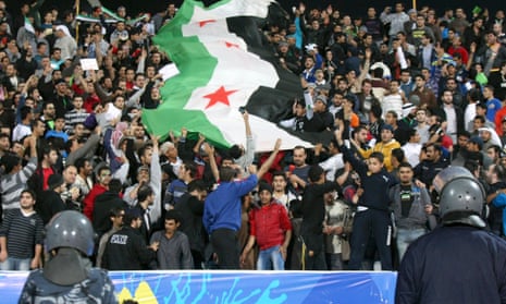 Fans of Syria hold the flag of the Syrian opposition during their West Asian Football Federation (WAFF) Championship final soccer match against Iraq in Kuwait City December 20, 2012.