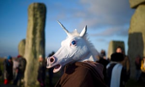 A reveller, dressed as a unicorn, celebrates the sunrise during the winter solstice at Stonehenge on Salisbury Plain in southern England.