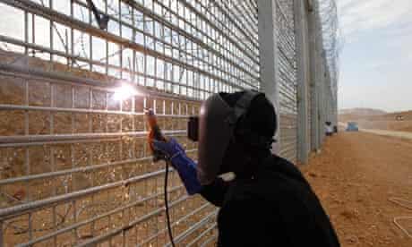 A Sudanese migrant worker works on the construction of the fence between Israel and Egypt