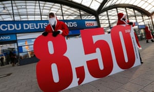 Demonstrating members of Germany's union association (DGB) dressed in Santa Claus costumes hold an placard with a number of 8.50 euro as a demanded minimum wage per hour prior to the opening of Germany's Christian Democratic Union (CDU)'s annual party meeting in Hanover, December 4, 2012