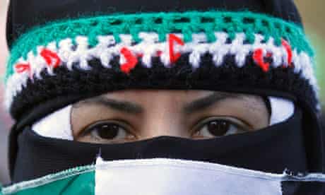 A Syrian woman is masked in the colours of the revolutionary flag during a protest march