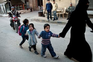 24hours: A woman walks with children in Kafar Taharim, north Syria