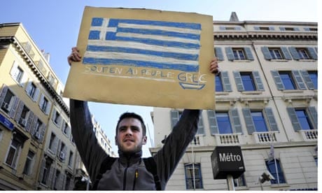 A man holds a placard bearing the Greek