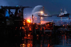 Manila: A fire boat sprays water as fire engulfs houses