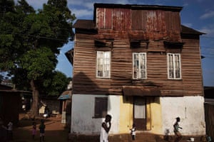 Sierra Leone Architecture: People walk past a traditional colonial-era Board House