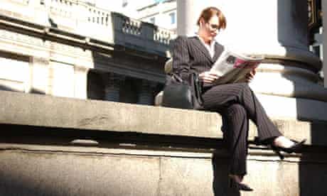 British business woman reading newspaper the city London UK professional director