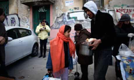 Immigrant families and homeless people receive food from a humanitarian group in Athens, Greece