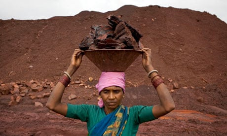 A woman carries lumps of iron ore at a Kalinga Mining Corp.