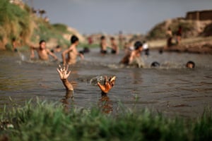 24 hours in pictures: An Afghan refugee boy takes a dip in a polluted a stream 