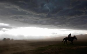24 hours: Karakorum, Mongolia: A Mongolian herder rides for shelter in a rainstorm 