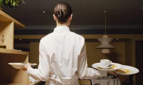 Waitress carrying dirty plates in restaurant, rear view