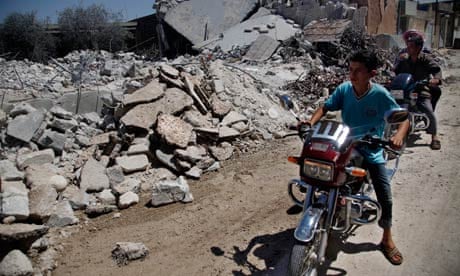 Young men on motorbikes survey damage purportedly caused by air strikes in the outskirst of Aleppo