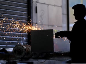 A worker builds and places protective metal bars on shops on the ground floor of a building housing Finance Ministry in Athens, Greece on 10 September 2012. The finance ministry was targetted by angry protestors during last year's demonstrations, with the shops suffering extensive damage.