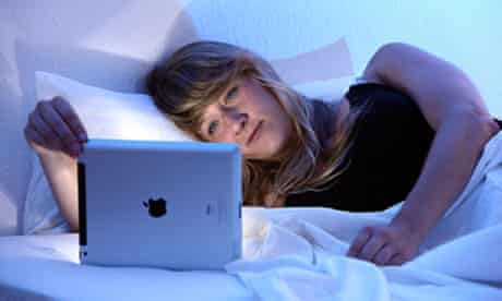A woman uses an iPad tablet in bed