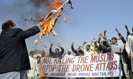 A Pakistani protester holds a burning US