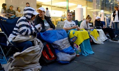 People sit in a queue outside Apple's flagship store in Sydney, Australia