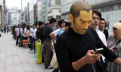 A customer wearing a mask of Steve Jobs waits in line outside the Apple store as the iPhone 5 smartphone goes on sale in Tokyo