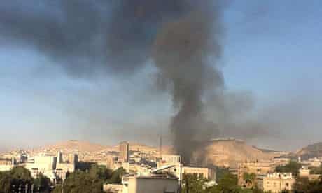 In Damascus, smoke rises from the site of twin explosions at a main military building