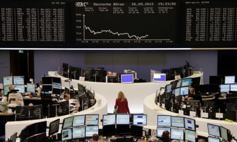 Traders are pictured at their desks in front of the DAX board at the Frankfurt stock exchange September 26, 2012. 