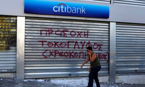 A woman covers her face to protect from teargas as she walks by a damaged Citibank branch following violent clashes between protesters and police in Athens' Syntagma square during a 24-hour labour strike September 26, 2012.