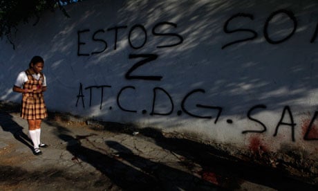 A girl looks at blood stains and a graffiti left by gunmen at a crime scene in Monterrey