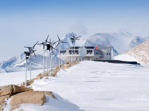Penguins in Antarctica: Princess Elisabeth Station with windturbines, solar panels & satellite dish