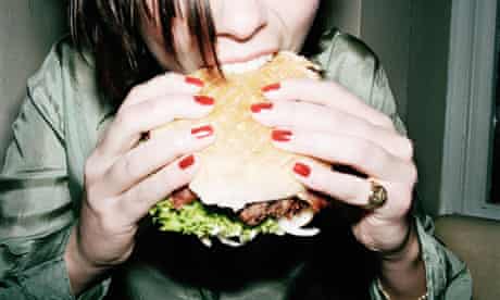 Young woman biting into burger