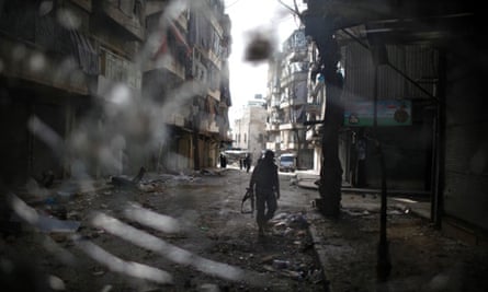 A fighter from the Islamist Syrian rebel group Jabhat al-Nusra is seen through a smashed bus window in Aleppo.