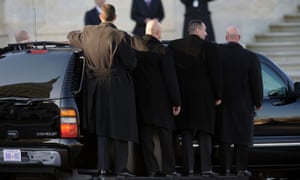 U.S. Secret Service agents ride on stepbar on the outside of their vehicle as they follow President Barack Obama as he leaves Capitol Hill.
