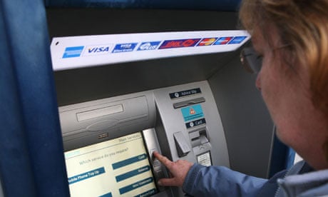 A woman uses a barclays bank ATM, cash machine