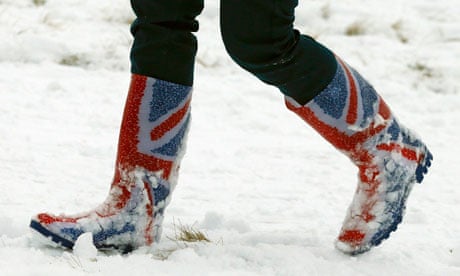 A woman walks through snow in Wellington boots printed with the union flag