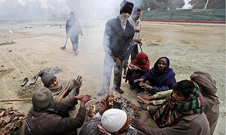 Municipal workers in Delhi warm themselves around a bonfire