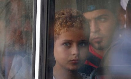 A migrant child looks out of the window of a police bus in Valletta, Malta