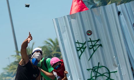 Protesters throw rocks from behind a shield outside the Libre oilfield auction in Rio de Janeiro