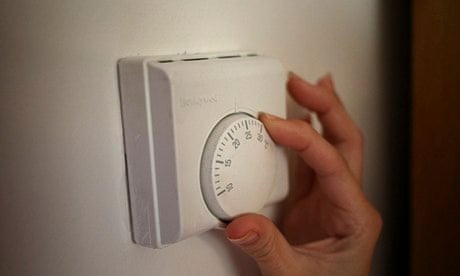 A person adjusts a central heating thermostat