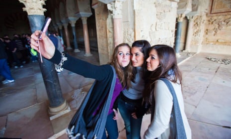 Spanish girls use a mobile phone to take a picture.