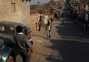 Alexandra Township: Man carries a young child the street