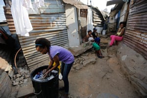 Alexandra Township: Woman washes clothes in a dustbin