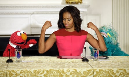 First lady Michelle Obama, flexes her arms for PBS Sesame Street's characters Elmo, left, and Rosita, right.